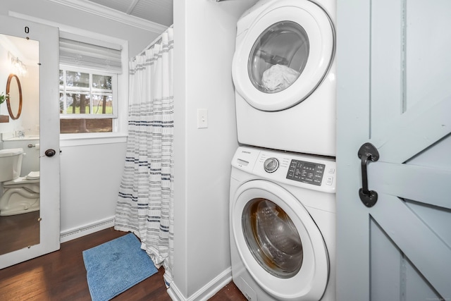 laundry area with laundry area, ornamental molding, wood finished floors, baseboard heating, and stacked washer / drying machine