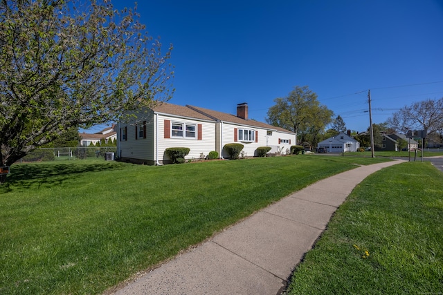 view of front of house with fence, a chimney, and a front lawn