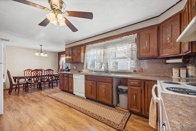 kitchen with brown cabinets, light wood-style floors, white appliances, backsplash, and visible vents