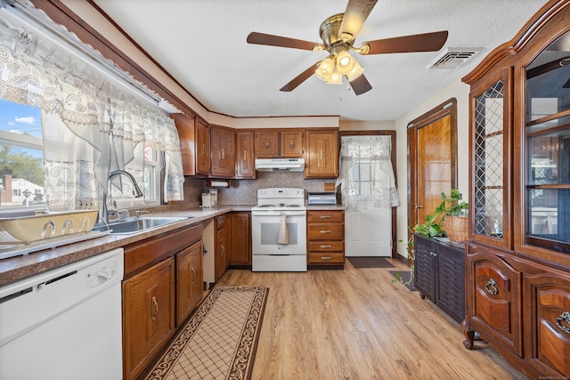 kitchen with a sink, white appliances, a ceiling fan, under cabinet range hood, and visible vents