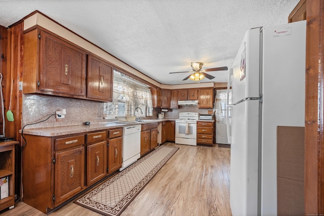 kitchen featuring light wood-style floors, light countertops, a textured ceiling, and white appliances