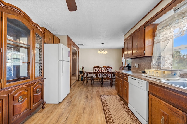kitchen with light wood-style floors, brown cabinetry, visible vents, and white appliances