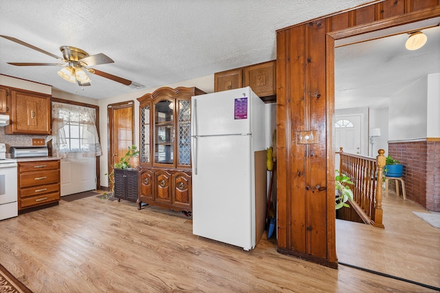 kitchen featuring ceiling fan, white appliances, light countertops, brown cabinetry, and light wood-type flooring