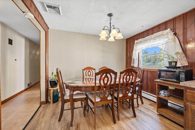 dining space with visible vents, a textured ceiling, light wood finished floors, and a chandelier