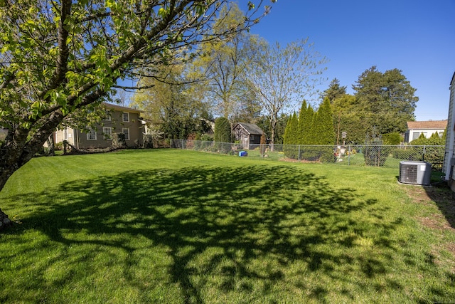 view of yard with central AC and fence