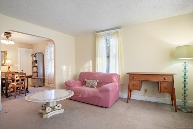 living room with arched walkways, light carpet, and a textured ceiling