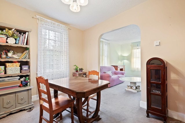 dining room featuring baseboards, arched walkways, and carpet