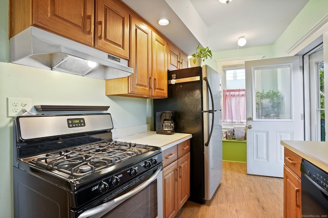 kitchen featuring a healthy amount of sunlight, stainless steel appliances, light wood finished floors, and under cabinet range hood