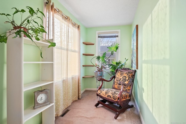 living area with baseboards, carpet flooring, a textured ceiling, and visible vents