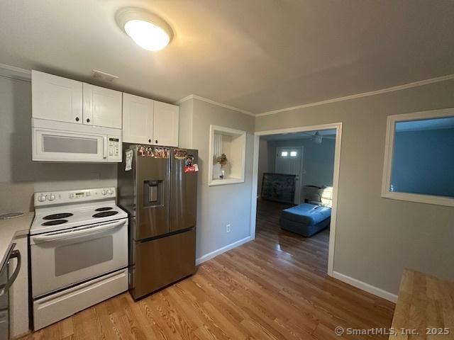 kitchen with white appliances, white cabinets, crown molding, and light wood-style flooring
