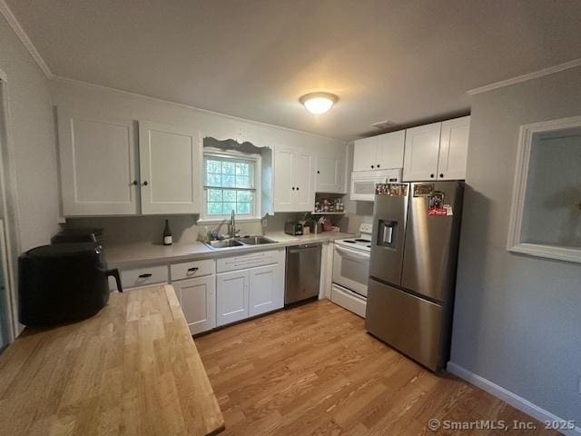 kitchen with crown molding, a sink, white cabinets, light wood finished floors, and stainless steel appliances