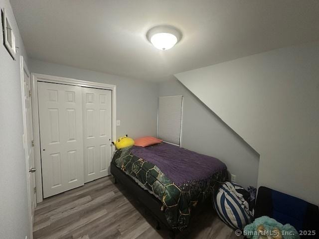 bedroom with visible vents, wood finished floors, and a closet