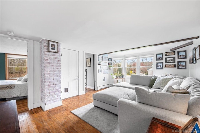 living room with baseboards, a baseboard heating unit, and light wood finished floors
