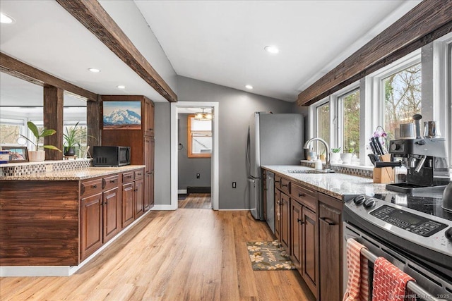 kitchen featuring a sink, light wood finished floors, stainless steel appliances, recessed lighting, and lofted ceiling