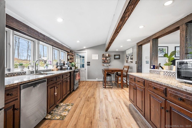 kitchen with appliances with stainless steel finishes, a sink, light wood finished floors, vaulted ceiling with beams, and recessed lighting