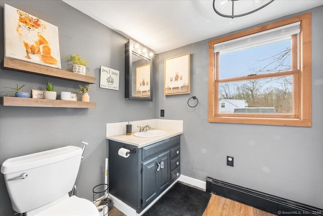 bathroom with vanity, toilet, baseboards, wood finished floors, and a baseboard heating unit