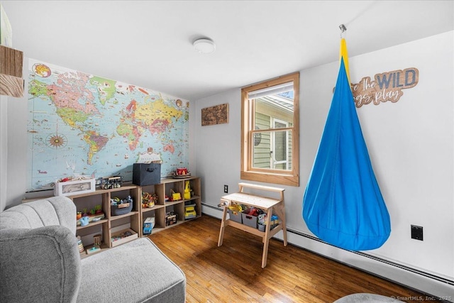 game room with baseboard heating, wallpapered walls, and wood finished floors