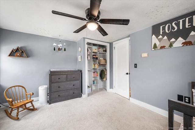 bedroom featuring carpet floors, a closet, baseboards, ceiling fan, and a textured ceiling