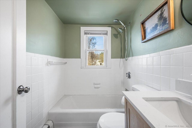 bathroom with tile walls, a wainscoted wall, vanity, toilet, and tub / shower combination