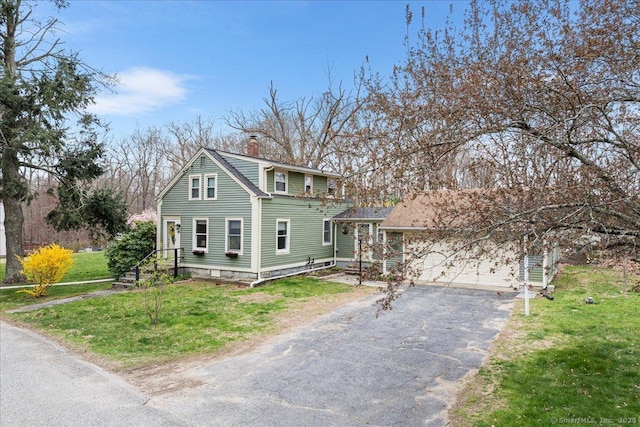 view of front of house featuring an attached garage, driveway, a chimney, and a front yard