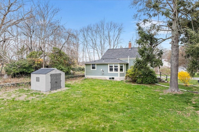 rear view of property featuring a chimney, roof with shingles, a storage shed, a lawn, and an outdoor structure