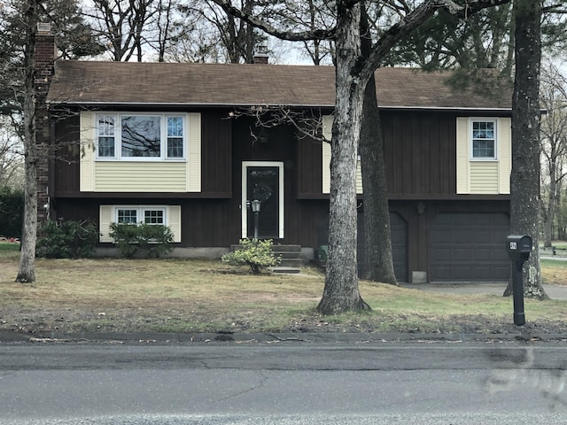 raised ranch featuring an attached garage and a chimney