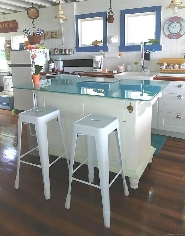 kitchen with a center island, a sink, dark wood finished floors, and a kitchen breakfast bar
