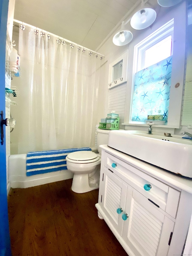 full bath featuring shower / bath combination with curtain, vaulted ceiling, wood finished floors, vanity, and toilet