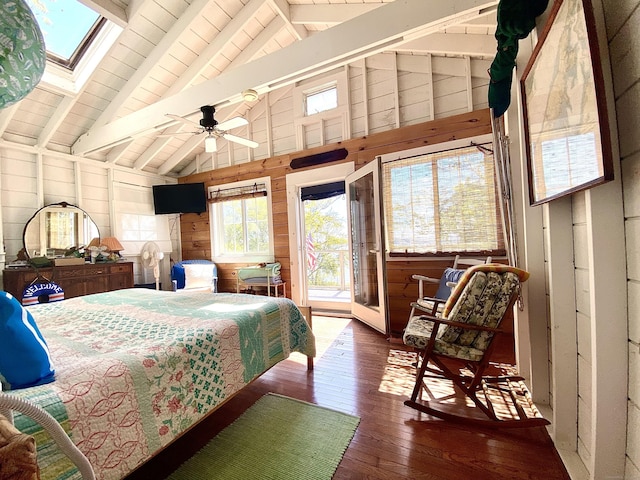 bedroom with wood-type flooring, wood walls, vaulted ceiling with skylight, and access to exterior
