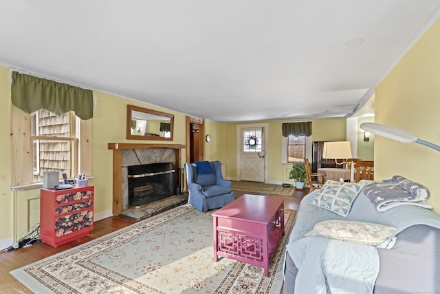 living room featuring baseboards, a fireplace with raised hearth, and wood finished floors