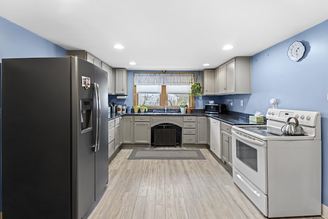 kitchen with a sink, appliances with stainless steel finishes, gray cabinetry, and dark countertops