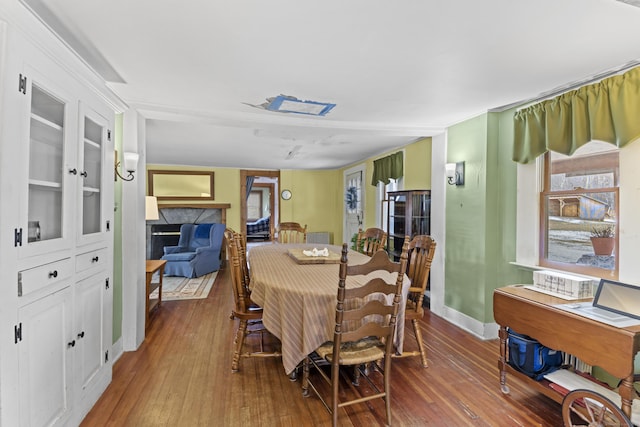 dining space featuring baseboards, hardwood / wood-style flooring, and a high end fireplace