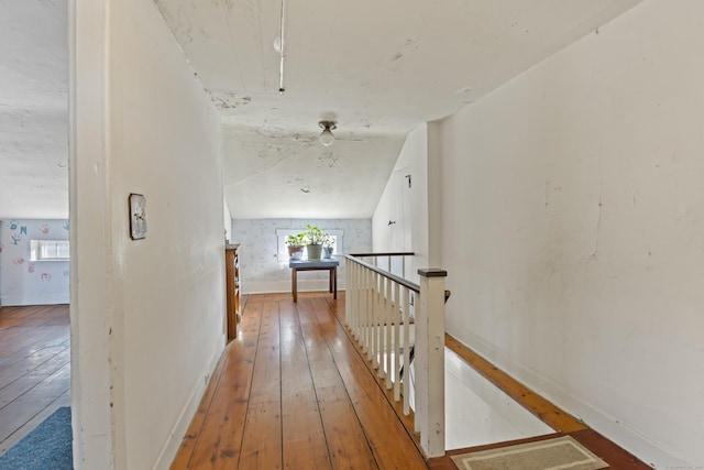 hall with wood-type flooring, baseboards, and an upstairs landing