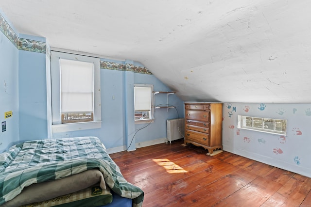 bedroom featuring baseboards, radiator, vaulted ceiling, and hardwood / wood-style flooring