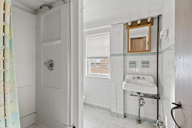 bathroom with wainscoting, a sink, tile patterned floors, tile walls, and a shower