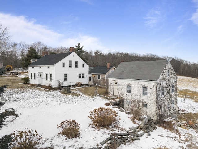 snow covered house featuring a chimney