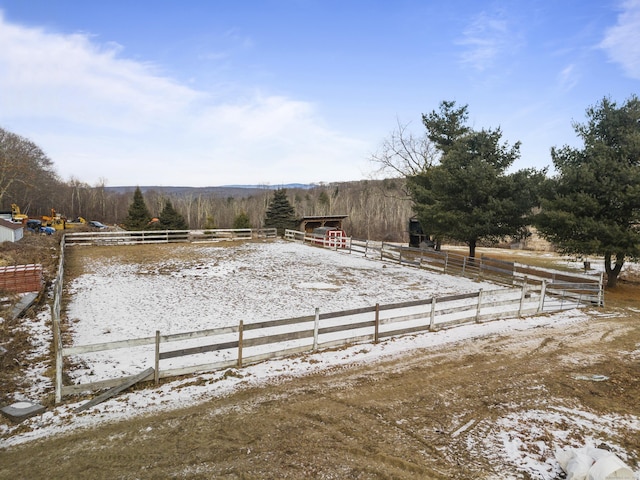 snowy yard featuring an enclosed area, an outbuilding, and a rural view