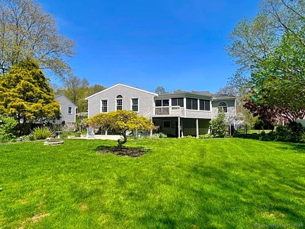 back of house with a lawn, fence, and a sunroom