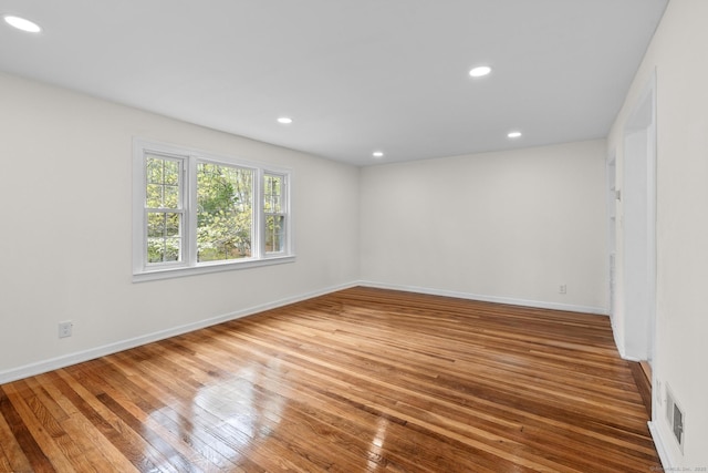 unfurnished room with baseboards, recessed lighting, visible vents, and hardwood / wood-style floors