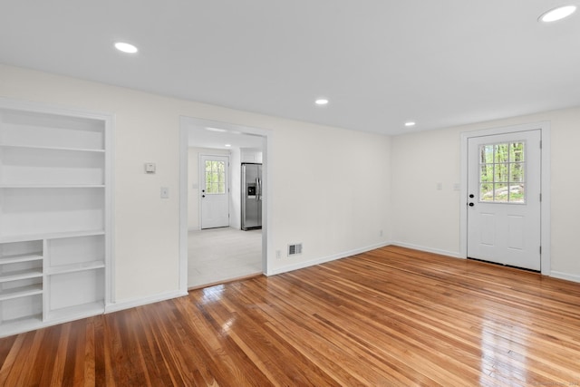 unfurnished living room featuring visible vents, recessed lighting, light wood-style flooring, and built in features