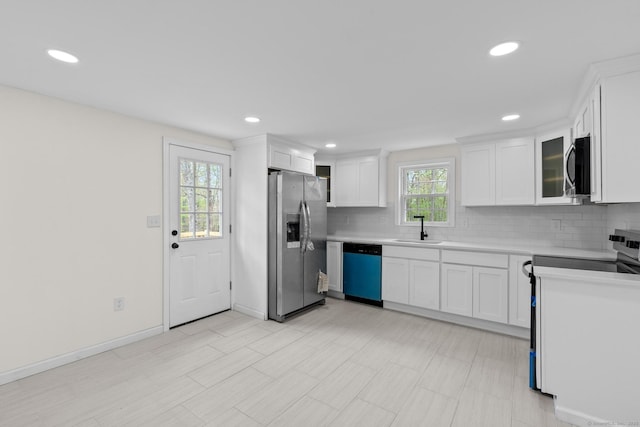 kitchen featuring light countertops, white cabinets, tasteful backsplash, a sink, and appliances with stainless steel finishes