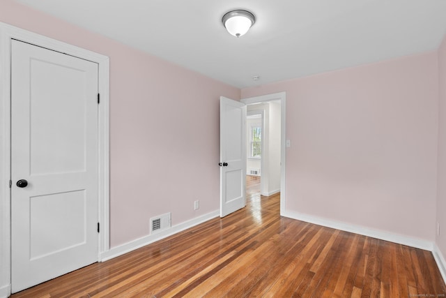 empty room featuring visible vents, baseboards, and light wood finished floors