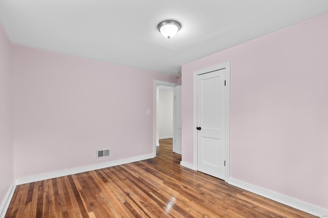 unfurnished room with baseboards, wood finished floors, and visible vents