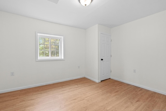 spare room featuring baseboards and light wood finished floors