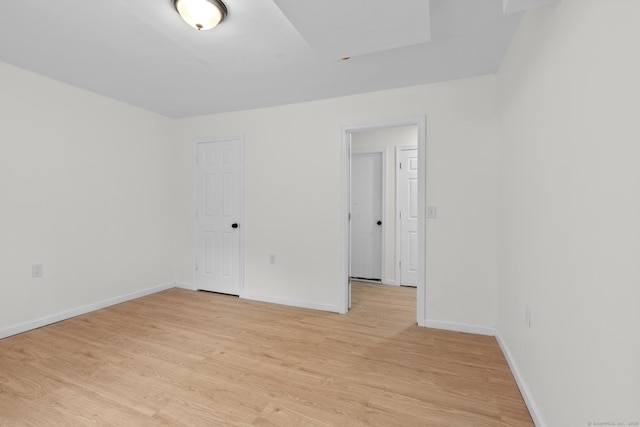 spare room with baseboards and light wood-style floors