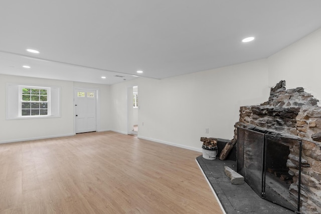 living room with recessed lighting, light wood finished floors, and a stone fireplace