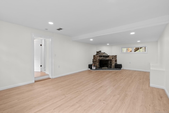 unfurnished living room with a stone fireplace, visible vents, baseboards, light wood finished floors, and recessed lighting