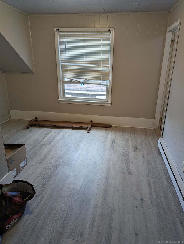 unfurnished room with baseboards, baseboard heating, and wood finished floors