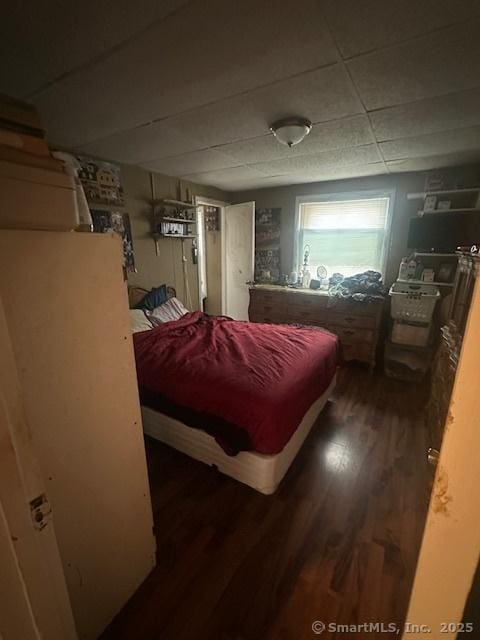 bedroom with a drop ceiling and wood finished floors