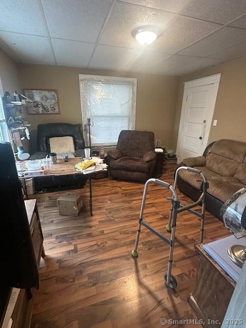 living area with a drop ceiling and wood finished floors